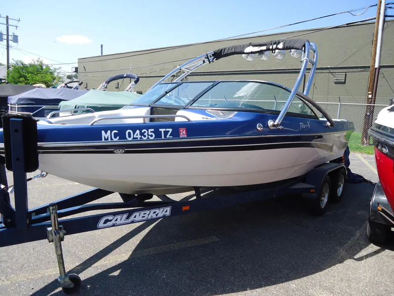 Slide: The Image of 2009 Calabria Pro V II boat on trailer, blue and white, parked outdoors. - 17