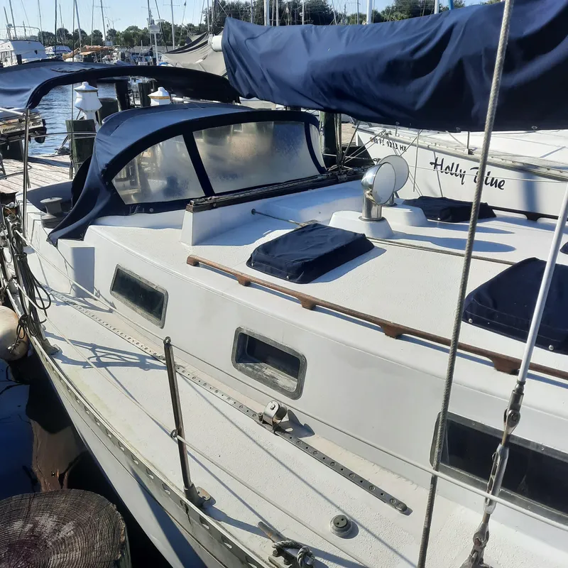 Slide: The Image of 1984 Cheoy Lee Sloop docked at marina, featuring blue canvas covers and sleek design. - 2