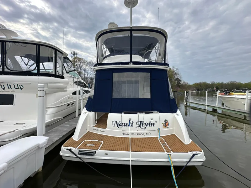 Slide: The Image of 2008 Meridian 391 Sedan docked, featuring "Nauti Glyn" name, blue canopy, and wooden deck. - 7