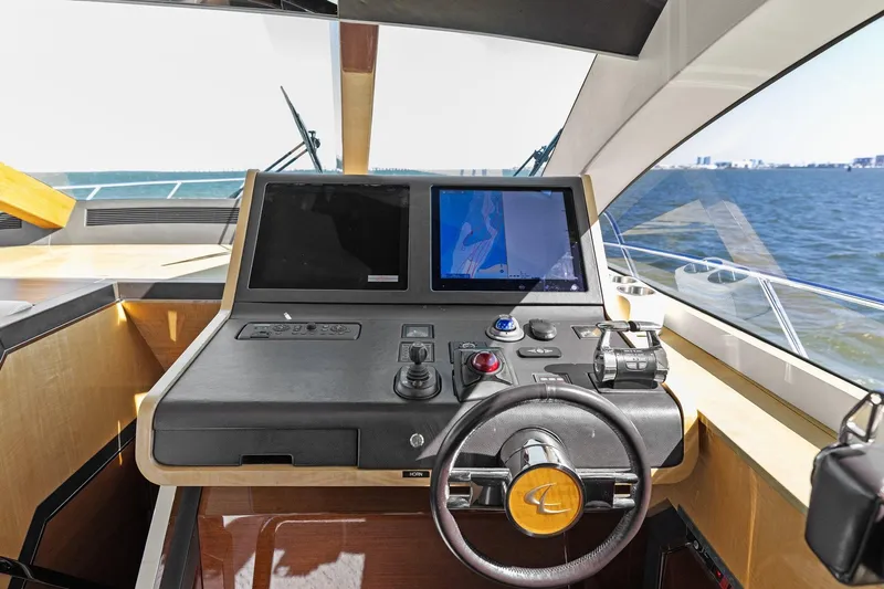 Slide: The Image of 2013 Cheoy Lee 76 Alpha yacht helm with dual screens and steering wheel, overlooking the ocean. - 48