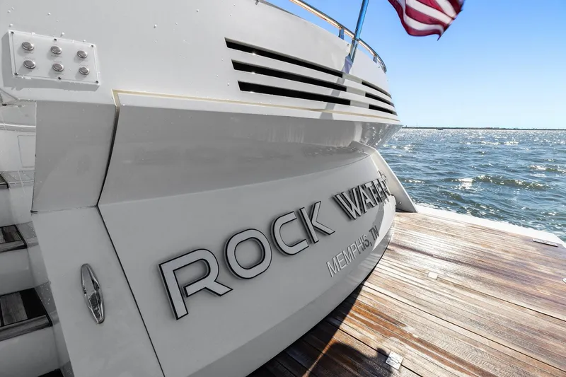 Slide: The Image of Cheoy Lee 76 Alpha yacht stern with "Rock Water" name, docked by the ocean. - 6