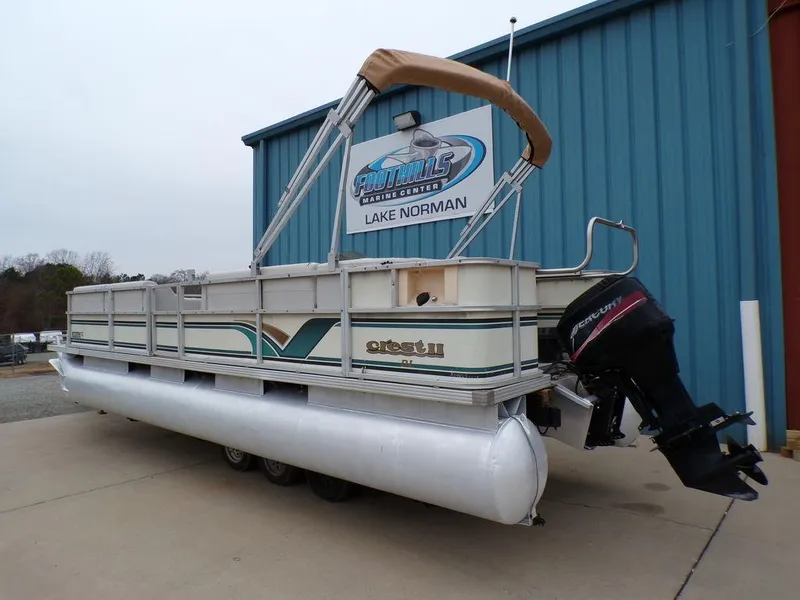 Slide: The Image of 2000 Crest II DL pontoon boat at Lake Norman, parked near a blue building. - 2
