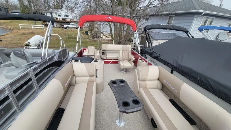 Slide: The Image of 2025 Bennington S Swingback 22 SSB pontoon boat with beige seating and red canopy. - 6