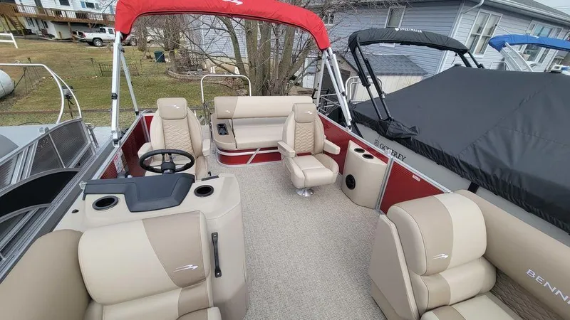Slide: The Image of 2025 Bennington S Swingback 22 SSB pontoon boat with beige seating and red canopy. - 7