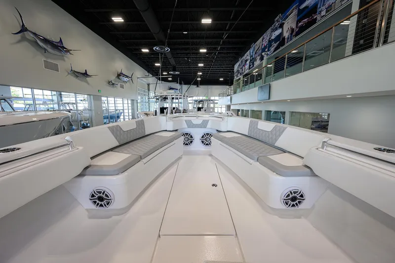 Slide: The Image of 2025 Contender 39 ST boat interior with cushioned seating and speakers in a showroom. - 18