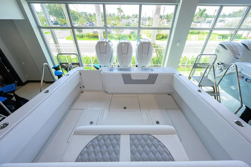 Slide: The Image of 2025 Contender 39 ST boat interior with triple outboard engines, showcased in a bright showroom. - 43