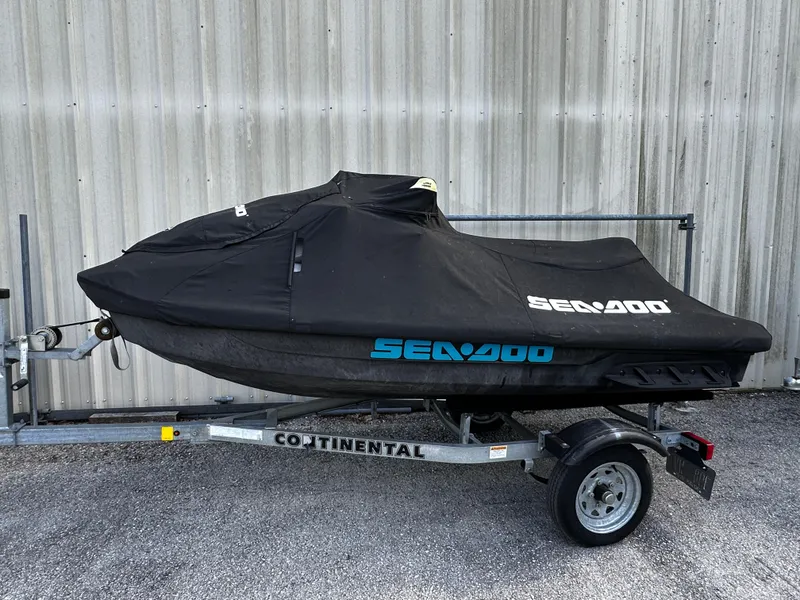 Slide: The Image of 2023 Sea-Doo Fish Pro Scout covered on trailer, parked by a metal wall. - 4