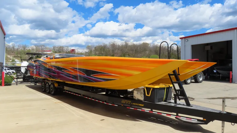 Slide: The Image of 2010 MTI 48 R/P powerboat with vibrant orange and black design on a trailer. - 2
