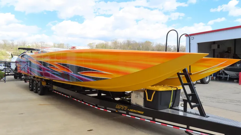 Slide: The Image of 2010 MTI 48 R/P powerboat with vibrant orange and yellow design on a trailer. - 38