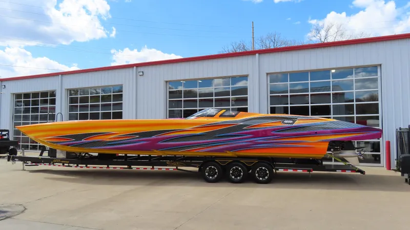 Slide: The Image of 2010 MTI 48 R/P speedboat with vibrant graphics on a trailer outside a garage. - 4