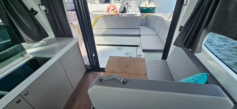 Slide: The Image of Interior of 2022 Beneteau Antares 11, featuring modern seating and compact kitchen area. - 15