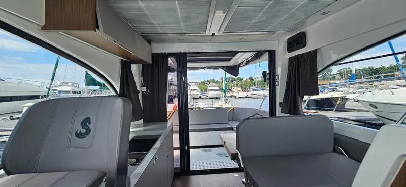 Slide: The Image of Interior view of 2022 Beneteau Antares 11 yacht, featuring modern seating and marina backdrop. - 16