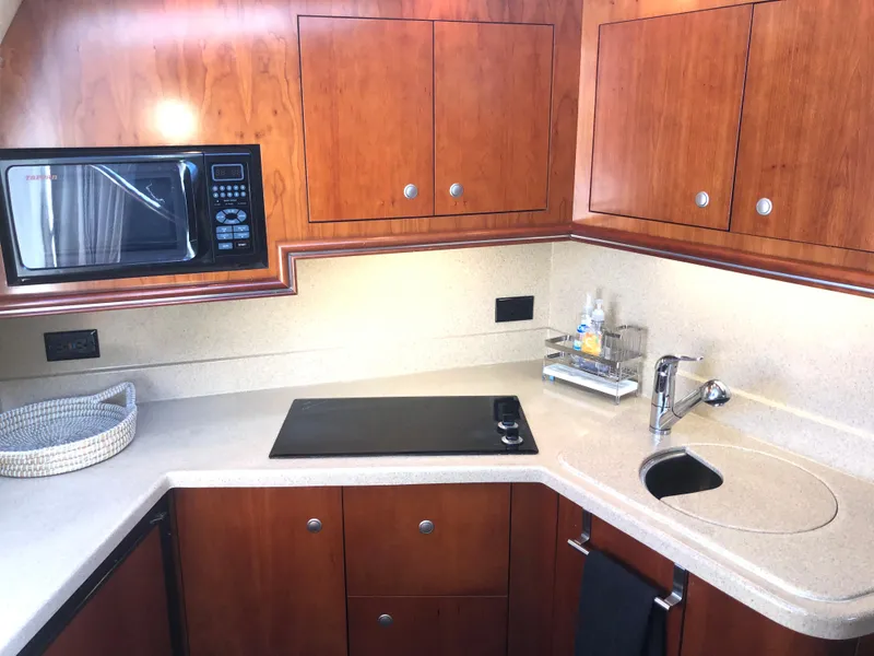 Slide: The Image of 2007 Cruisers Yachts 340 Express kitchen with microwave, stove, and wooden cabinets. - 31