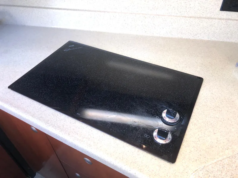 Slide: The Image of Stovetop in 2007 Cruisers Yachts 340 Express galley, featuring sleek black design. - 33