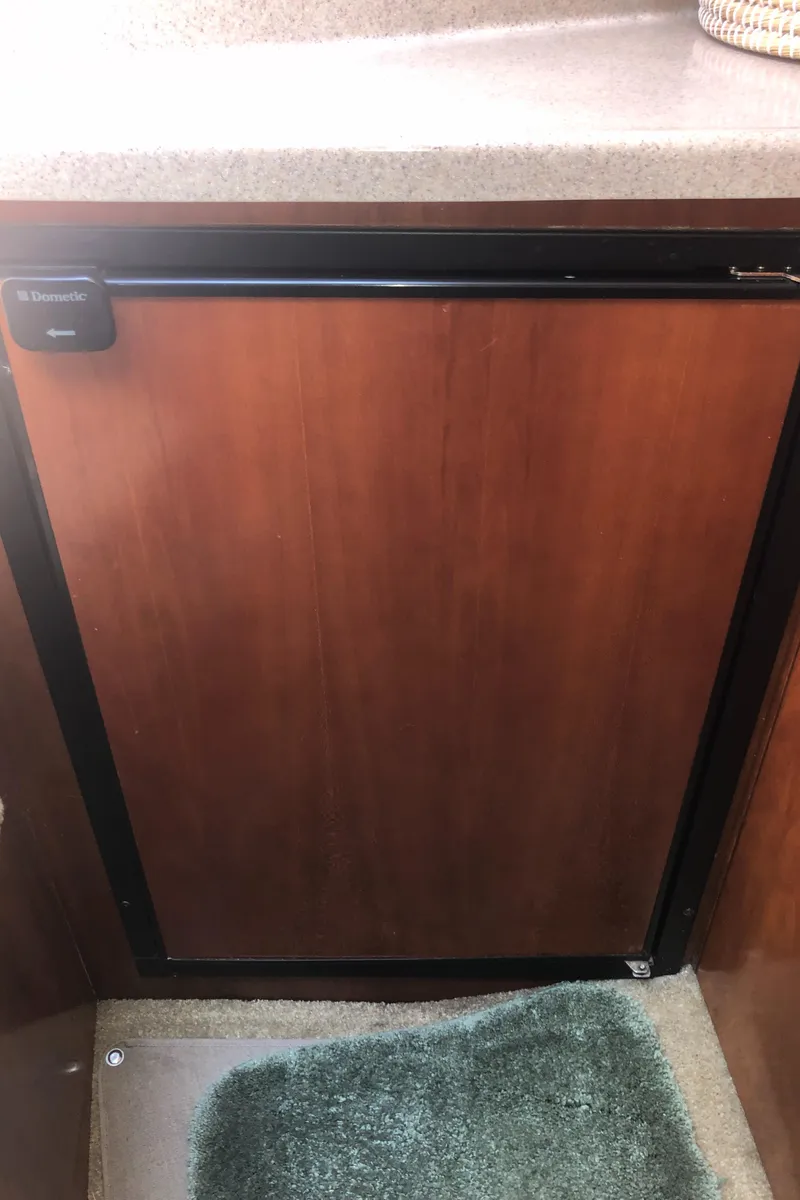 Slide: The Image of 2007 Cruisers Yachts 340 Express interior with wooden cabinetry and compact refrigerator. - 34