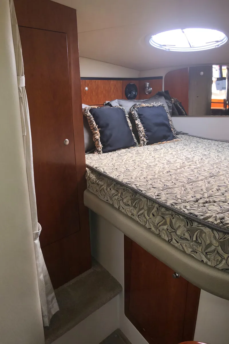 Slide: The Image of 2007 Cruisers Yachts 340 Express cabin with bed, wooden cabinetry, and circular window. - 42