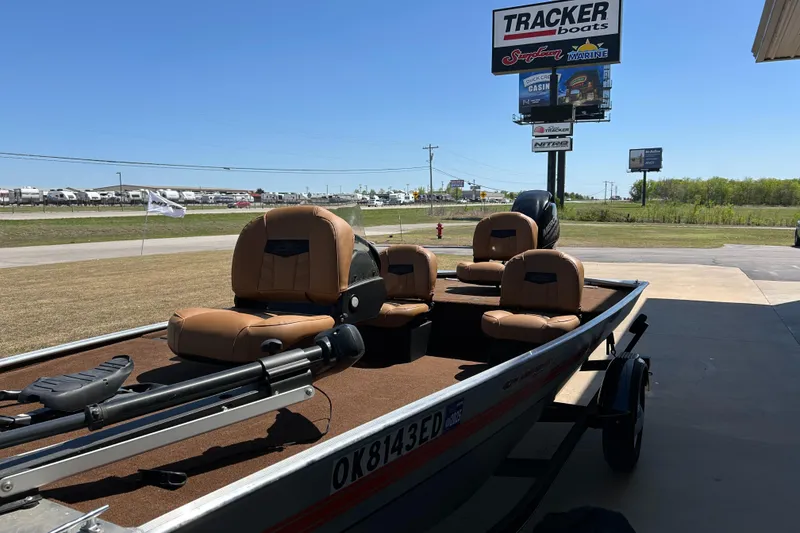 Slide: The Image of 2018 Bass Tracker Heritage boat with tan seats, parked near a dealership under a clear blue sky. - 10