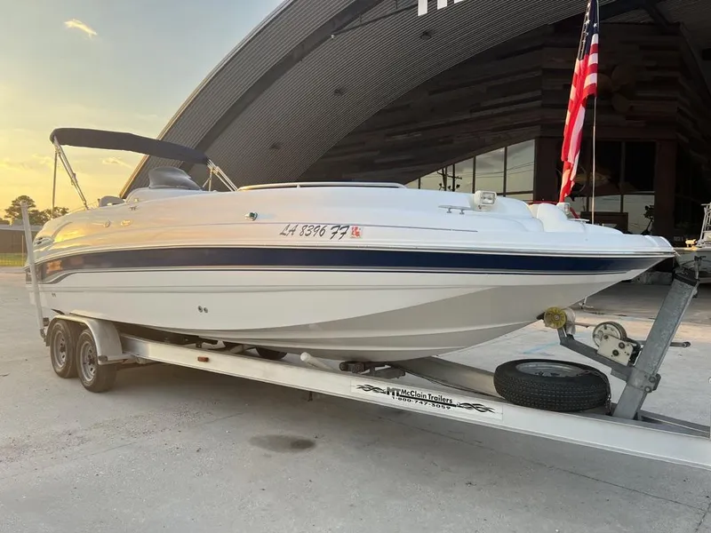 Slide: The Image of Chaparral Sunesta 252 boat on trailer, 2000 model, parked near a building with an American flag. - 5