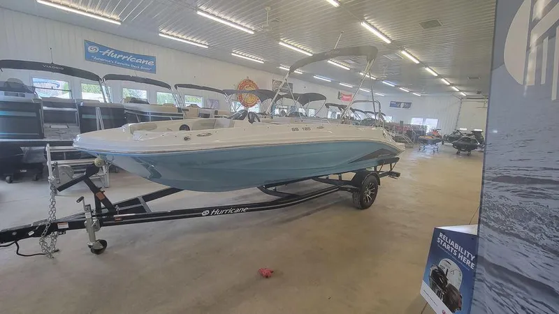Slide: The Image of 2025 Hurricane SunDeck Sport 185 OB boat displayed indoors on a trailer. - 11
