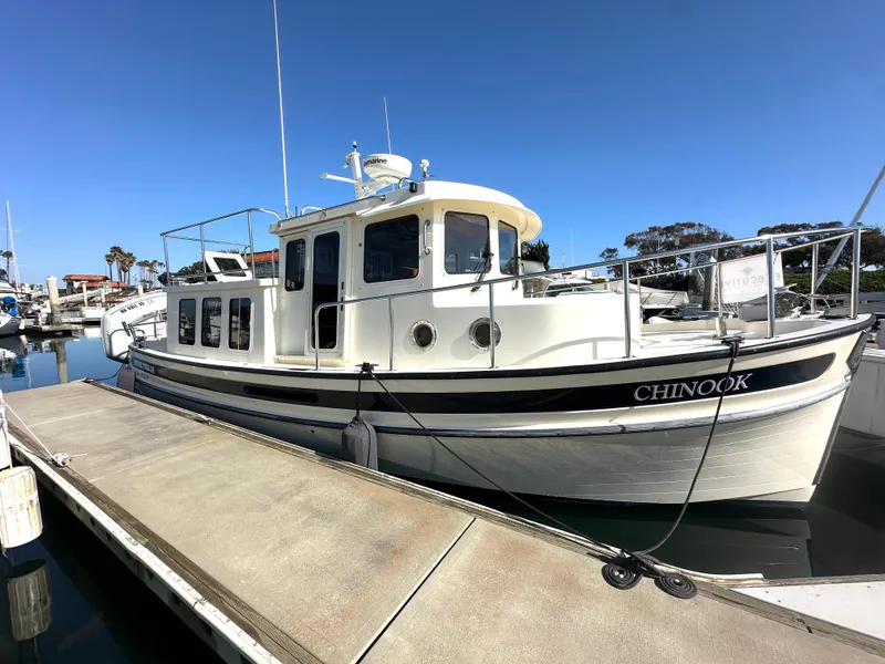 The Image of 2004 Nordic Tug 32 docked at marina under clear blue sky. - 1