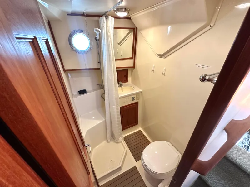 Slide: The Image of Bathroom interior of 2004 Nordic Tug 32, featuring shower, toilet, and porthole window. - 10
