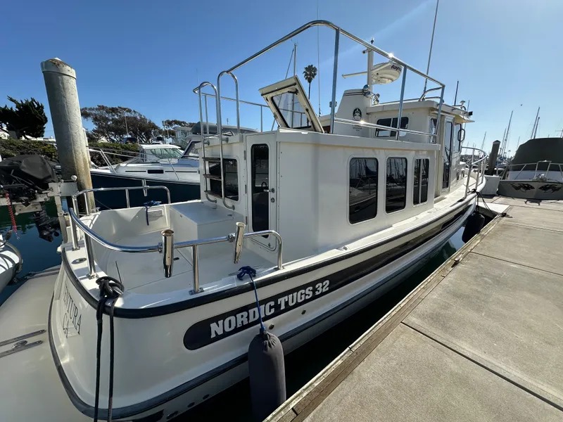 Slide: The Image of 2004 Nordic Tug 32 docked at marina, side view with clear sky. - 2
