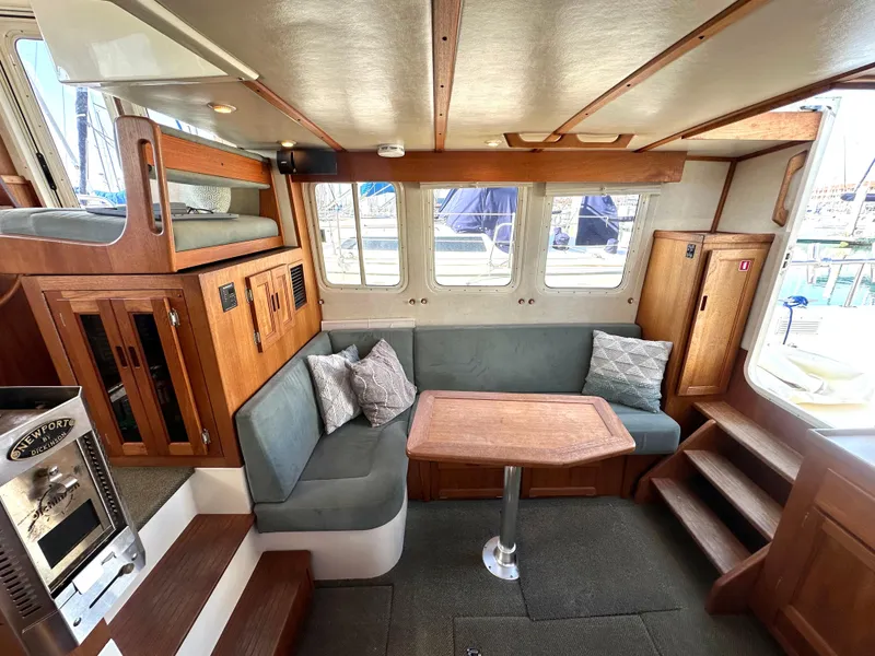 Slide: The Image of 2004 Nordic Tug 32 interior with cozy seating, wooden accents, and large windows. - 7