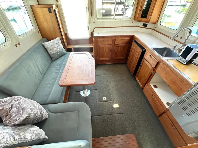 Slide: The Image of Interior of a 2004 Nordic Tug 32, featuring a cozy seating area and compact kitchen. - 8