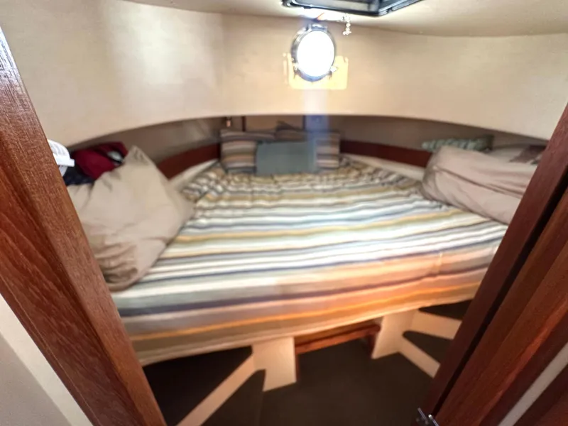 Slide: The Image of Cozy cabin interior of 2004 Nordic Tug 32 with striped bedding and porthole window. - 9