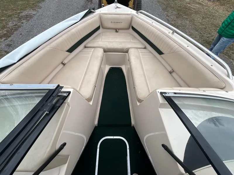 Slide: The Image of 1995 Celebrity 180 Bowrider boat interior with beige seating and green carpet. - 12