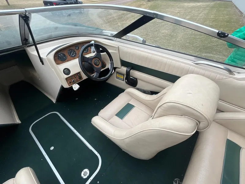 Slide: The Image of Interior of a 1995 Celebrity 180 Bowrider boat with beige seating and green accents. - 5