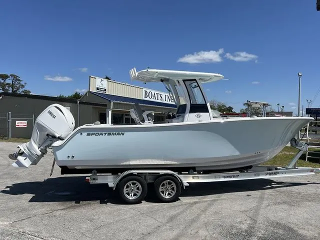 Slide: The Image of 2025 Sportsman Open 252 boat on trailer, parked outside dealership under clear blue sky. - 15