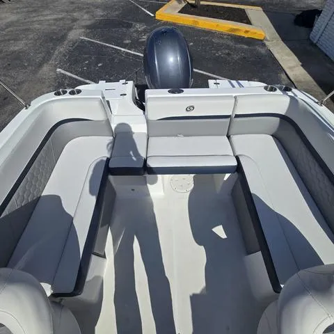Slide: The Image of 2023 Hurricane Sundeck Sport 218 OB boat interior with seating and motor in a parking lot. - 9