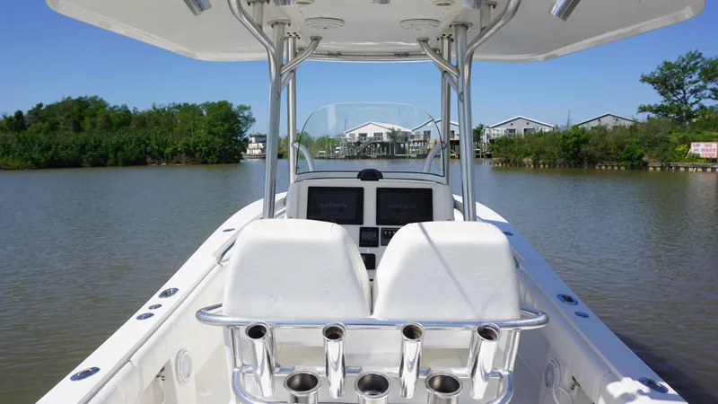 Slide: The Image of 2015 Regulator 25 boat interior with dual seats and rod holders on a calm river. - 11