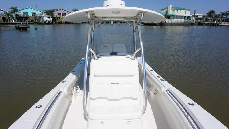 Slide: The Image of 2015 Regulator 25 boat on calm water, featuring a sleek white design and spacious deck. - 14