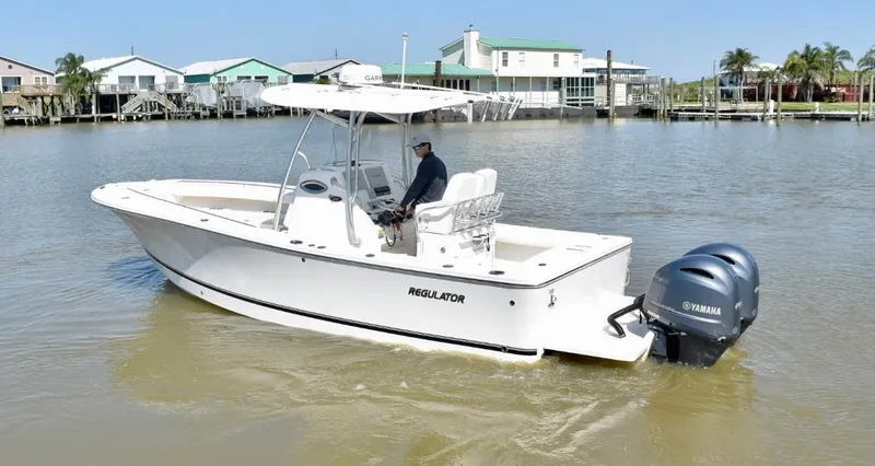 Slide: The Image of 2015 Regulator 25 boat with Yamaha engine on calm water near waterfront homes. - 2