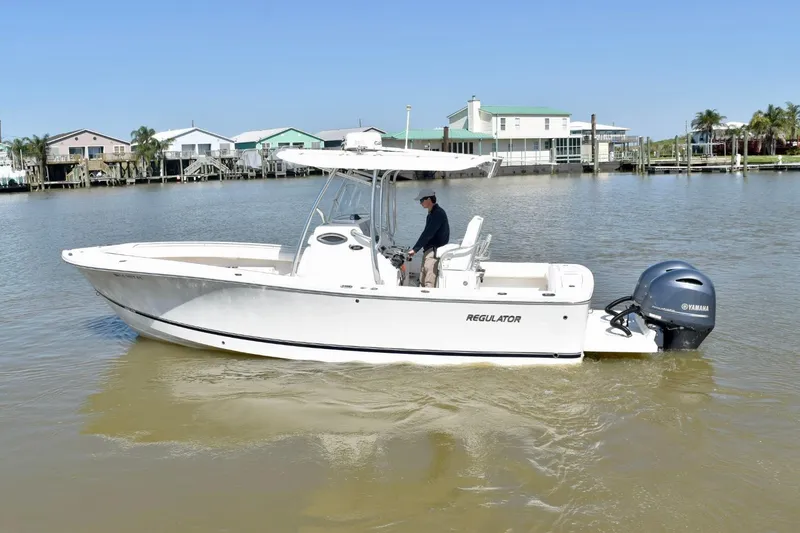 Slide: The Image of 2015 Regulator 25 boat on calm water with Yamaha engine, near waterfront homes. - 8