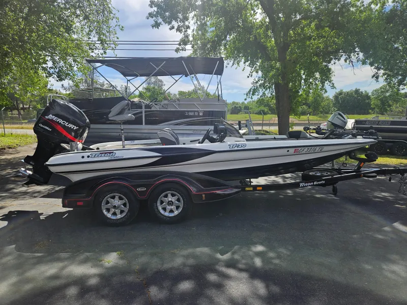 Slide: The Image of 2000 Triton TR 20 boat with Mercury engine on trailer, parked under trees. - 1