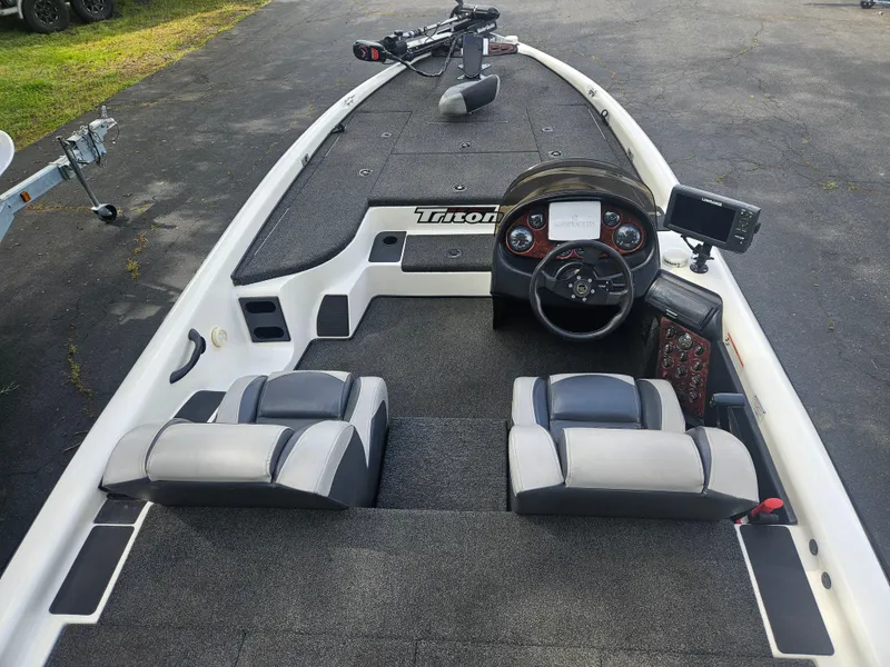 Slide: The Image of 2000 Triton TR 20 boat interior with steering wheel and seating, parked on pavement. - 3