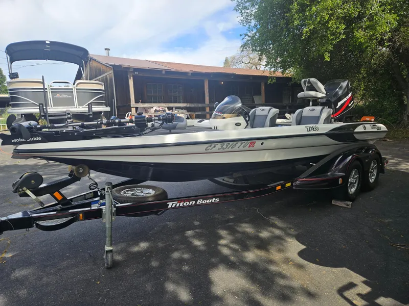 Slide: The Image of 2000 Triton TR 20 boat on trailer, parked outdoors near trees and a building. - 4