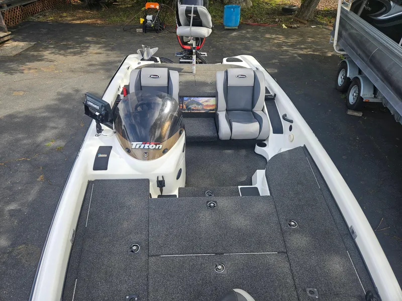 Slide: The Image of 2000 Triton TR 20 boat with gray seating and deck, parked on pavement. - 7