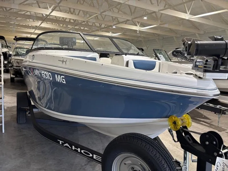 Slide: The Image of 2020 Tahoe 450 TF boat in showroom, blue and white design, on trailer. - 2