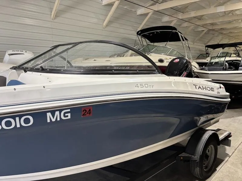 Slide: The Image of 2020 Tahoe 450 TF boat in showroom, blue and white exterior, on trailer. - 3
