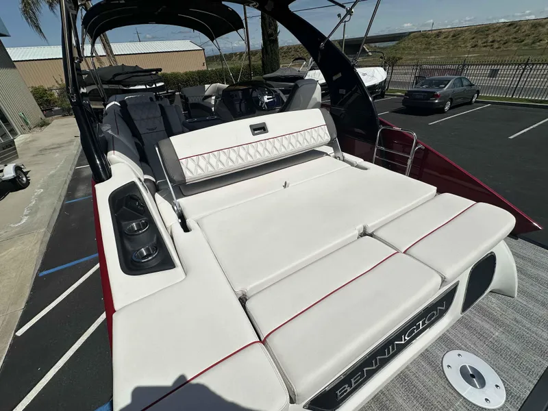 Slide: The Image of 2025 Bennington 25 RXSB boat with luxurious seating and sleek design in a parking lot. - 17