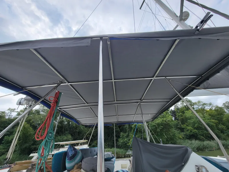 Slide: The Image of 2011 Lagoon 450 catamaran with a covered deck, ropes, and lush greenery in the background. - 36