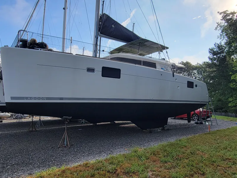 Slide: The Image of Lagoon 450 catamaran from 2011 on land, with masts and sails visible. - 47