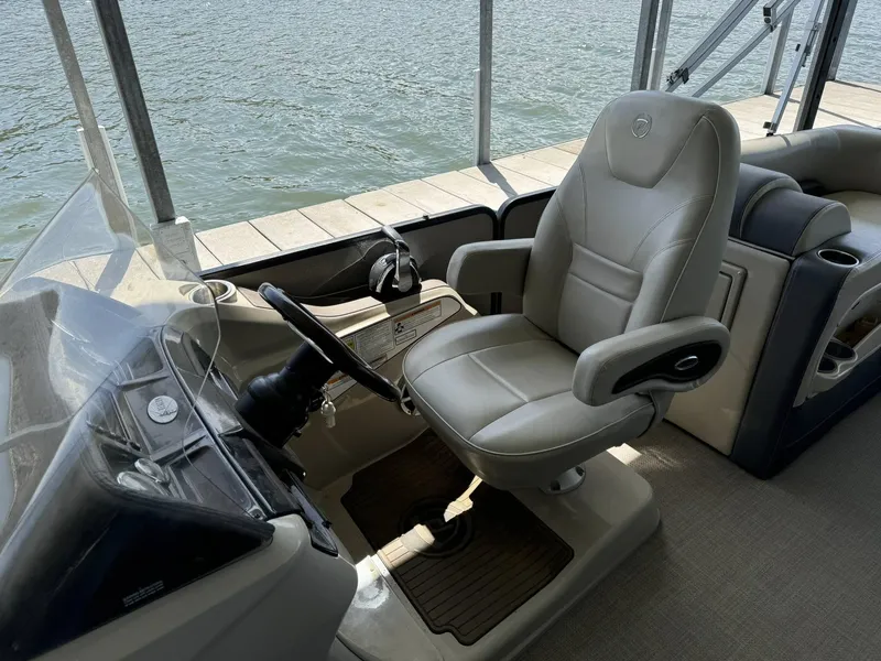 Slide: The Image of Captain's chair and helm of 2015 Premier 270 Grand Isle SL boat by the water. - 15
