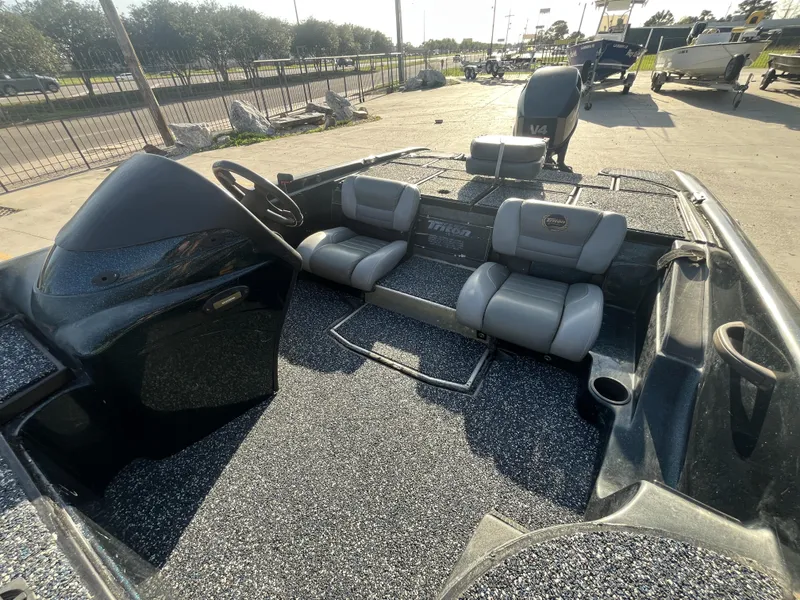 Slide: The Image of 1998 Triton Tr-17 boat interior with gray seats and steering wheel, parked outdoors. - 11