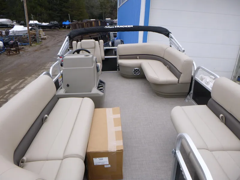 Slide: The Image of 2025 Sun Tracker Party Barge 16 DLX pontoon boat with beige seating and a cardboard box. - 10