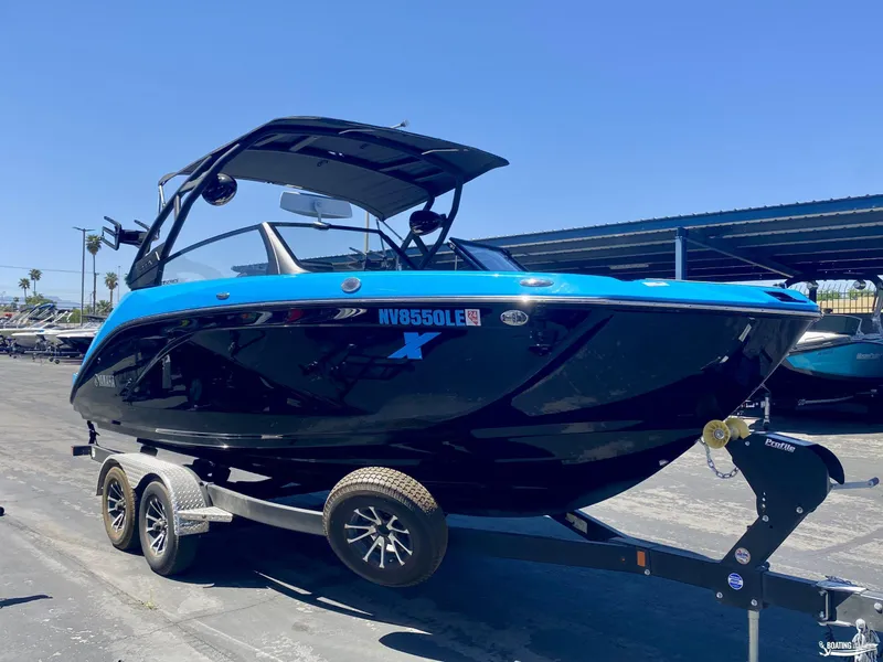 Slide: The Image of 2023 Yamaha Boats 222XE in blue and black on a trailer, parked outdoors. - 2
